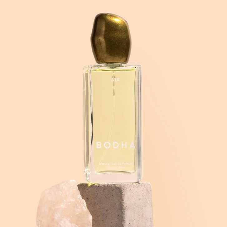 Bodha | Elemental Eau de Parfum | Styled Image | Clear glass bottle with gold top on stone with beige background