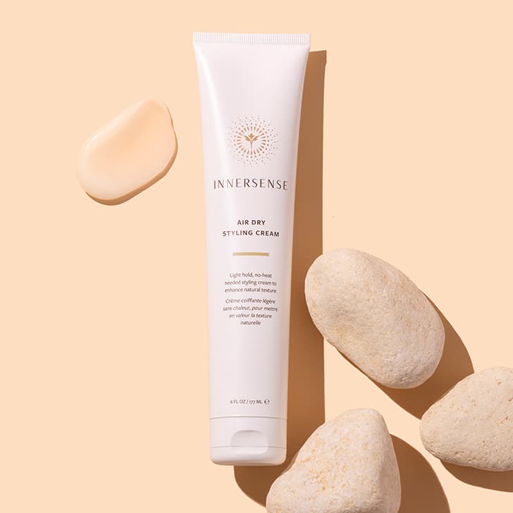 Innersense | Air Dry Styling Cream | Styled image flat lay, white tube on peach background with peach product swatch