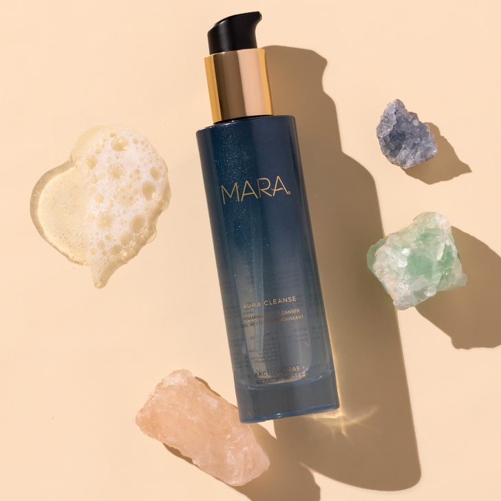 MARA | Aura Cleanse Gel Cleanser | Styled image of blue bottle flat lay on peach background with foaming swatch