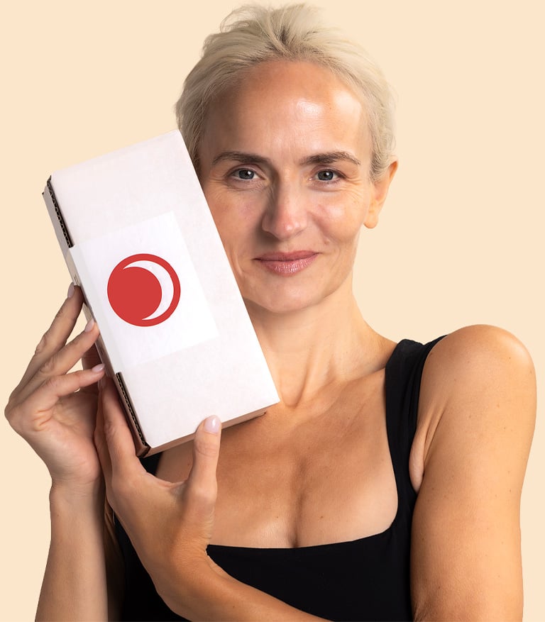A woman holding the Beauty Heroes subscription box, smiling