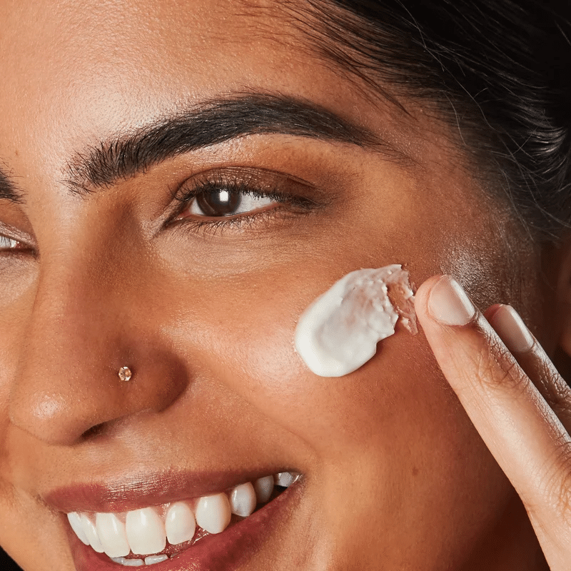 A model applying a barrier repair cream on her cheek